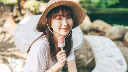 Portrait of cute asian teenager woman eating ice cream at outdoor garden.