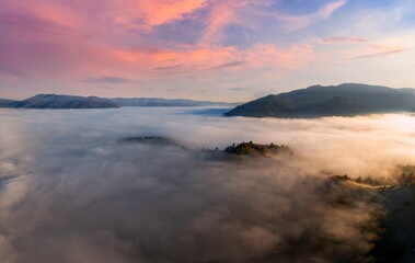 Mountains with colorful trees covered with layer of fog