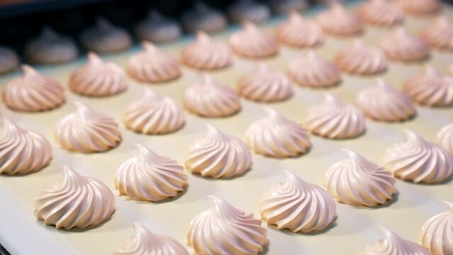 Marshmallow candies appearing from the automation line on food factory. Delicious desserts close on blurred background.