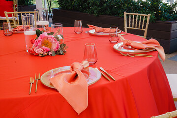 Wine glasses on round banquet table served Red tablecloth Red color decoration of wedding table set Floral arrangement Dishes, wine glasses, and napkins Catering concept 