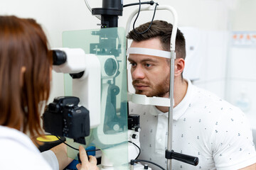 Naklejka na ściany i meble Optometrist checking patient eyes. Clinical specialist examining vision in modern hospital.