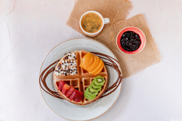 waffles with peach, strawberries, ice cream, coffee on pink table