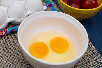 Two raw eggs in a white bowl