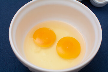 Two eggs in a white bowl, top view