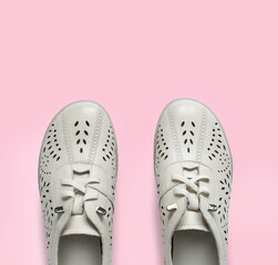 Pale white female shoes on pink backdrop. Flat lay, top view trendy fashion feminine background.