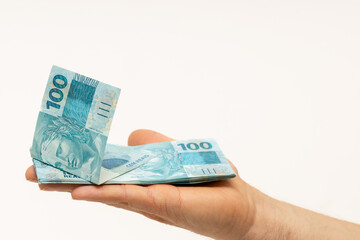 Brazilian money lying on an outstretched hand, isolated on white, Many 100 Reais banknotes, space for text, Economic and business concept