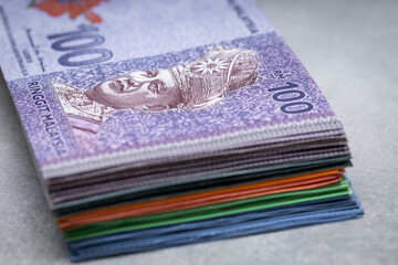 A bundle of Malaysian money, ringits on a gray table top, 100 banknote on top, Economic and business concept