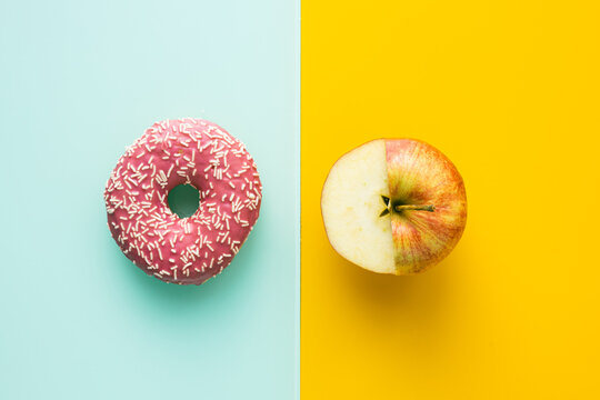sweet donuts on green pastel background and apple on yellow, Concept of healthy eating and healthy sugar in diet, healthy, unhealthy 