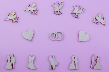 wooden figures of couples, cupids, hearts, rings wedding card on pink background