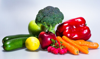 vegan food: radishes, carrots, zucchini, red pepper, apples, lemon and broccoli