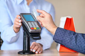 A man makes online purchases using a mobile terminal. Swipes a plastic card through the terminal reader.
