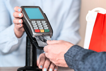 A young female seller provides the buyer with a terminal for online payment for purchases with a plastic card.