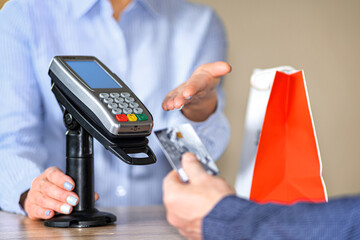 The girl seller points to the terminal to make a purchase with a plastic card.
