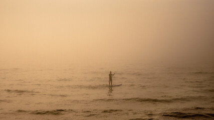 Fototapeta premium Person swimming on the water in the fog
