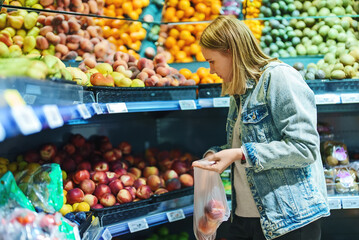 Pretty woman buys nectarines in a store.