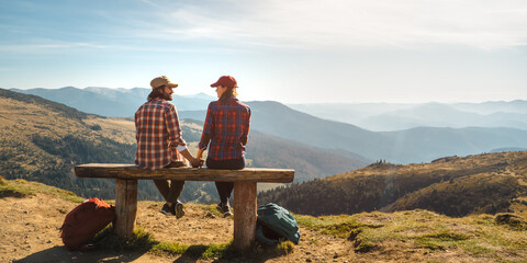 Couple of hikers with backpacks enjoying valley landscape view from the top of a mountain.Happy...