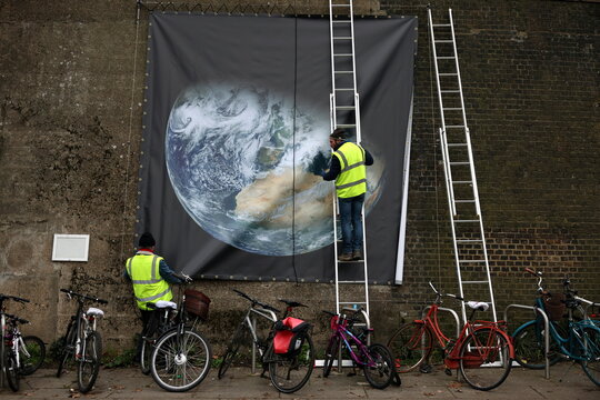 Members of Abundance London install a NASA public domain image of the planet on the railway embankment in Chiswick