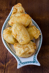 Fried cod served in serving dish on wooden background