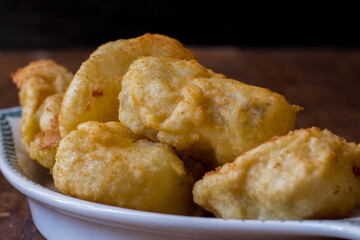 Fried cod served in serving dish on wooden background