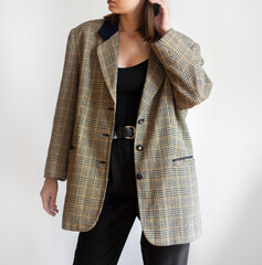 Woman wearing oversized check blazer and black trousers isolated on white background