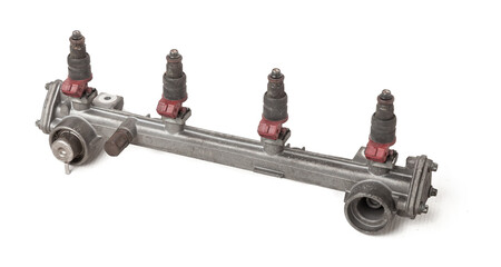 Close-up on a car fuel rail with injectors for supplying gasoline to a four cylinder engine on a white isolated background. Spare parts catalog