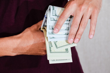 man holds a wad of dollars in his hands. US Dollars