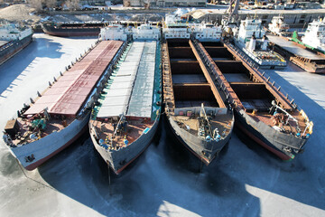 Fototapeta na wymiar Cargo transportation. a lot of old bulk carriers. View from the nose. Winter layup of ships at the mouth of the Volga River in Volgograd. Russia