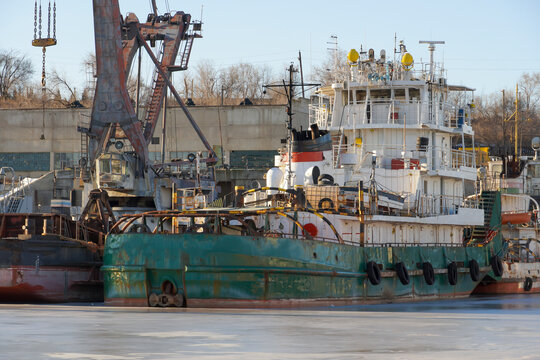 Motor ship pusher tug in green paint at winter parking in the backwater of the Volga River