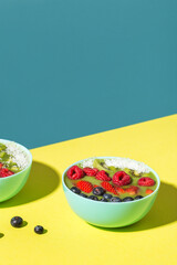 smoothie bowl with fresh berries and fruits in blue plate on yellow dark shadow