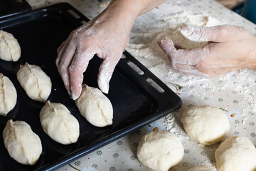 Home baking. Woman making pies and putting them on baking sheet. 