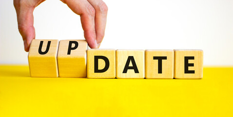 Date or update symbol. Businessman turns wooden cubes and changes the concept word date to update. Beautiful yellow table, white background, copy space. Business and date or update concept.