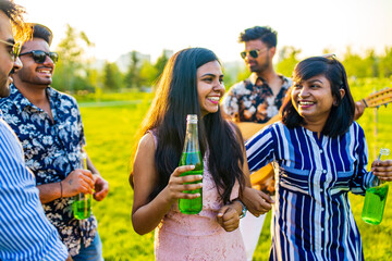 pakistanian happy best friends partying with lemonade and beer in summer park