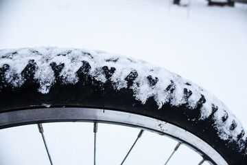 Winter bike ride. Bicycle wheel in the snow close-up.