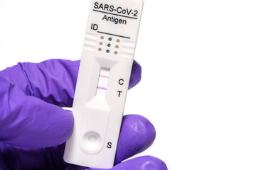 hand holding COVID-19 rapid antigen test positive result, immunochromatography of antibodies to detect infections