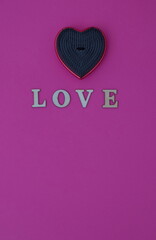 The word love on a pink background with a heart-shaped hair brush. Minimalistic scene.