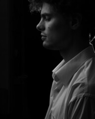 Caucasian thoughtfull man looking down portrait in white shirt in black and white