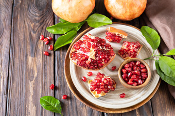 Ripe juicy pomegranate fruits in a wooden bowl on a rustic table. Diet and healthy food. Copy space.