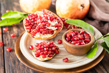 Ripe juicy pomegranate fruits in a wooden bowl on a rustic table. Diet and healthy food.