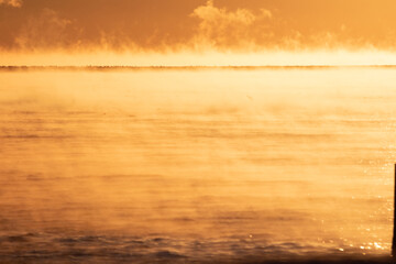Fototapeta na wymiar Steam fog rising over lake at sunrise