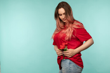 Portrait of a beautiful young woman with a red flower on a blue background in the studio