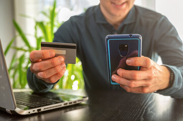 Mann kauft online mit Smartphone und zahlt mit Kreditkarte