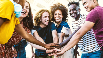 Multiracial happy young people putting their hands on top of each other - Diverse friends unity...