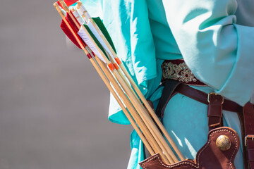 A man with a belt on which arrows from a bow hang.