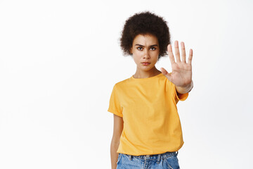 Stop this, stay away. Serious and confident Black girl extend palm, showing no, prohibit gesture,...