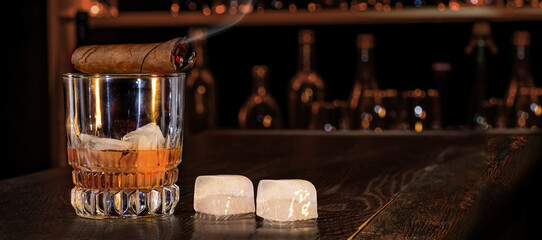 Cigar, elegant glass of brandy on the bar counter. Alcoholic drinks, cognac, whiskey, port, brandy,...