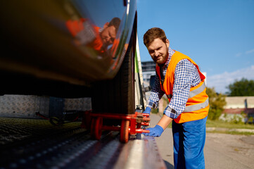 Tow truck operator fixing the car on platform