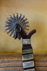 close up on the detail of a beautiful authentic western wear cowboy spur on a wooden shelf - obrazy, fototapety, plakaty