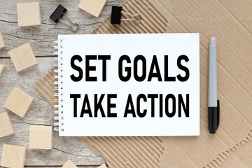 set goals take action notebook on a wooden table