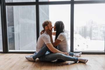 Couple in love tenderly hugs in a cozy home environment and panorama window