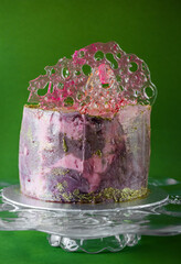 Gorgeous lilac, pink and gold glitter cake on green background. The concept of the Original design of desserts.